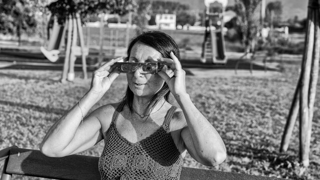 Girl observing celestial event in park with dramatic monochrome atmosphere