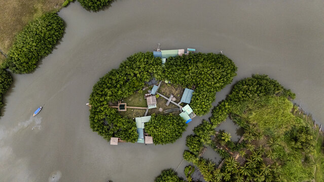 Aerial view of the island of Gogotinkpon, featuring lush vegetation, wooden structures, and walkways surrounded by river waters in Kpomasse, Mono, Benin.