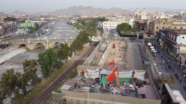 Aerial view of the Centro Historico in Lima, featuring the Rimac River, historic colonial architecture, and an archaeological excavation site with a large orange sculpture, Lima, Lima, Peru.