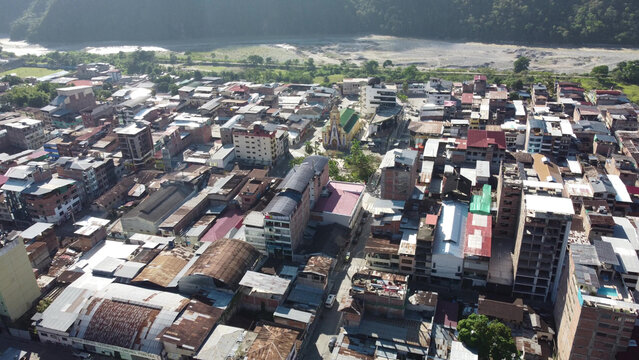 Aerial view of the town of La Merced featuring dense urban buildings, a prominent central church, and a riverbed in the background in La Merced, Junin, Peru.