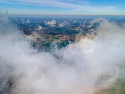 Aerial view of a glory optical phenomenon appearing in the clouds above the green landscape of Vidzeme, Latvia.
