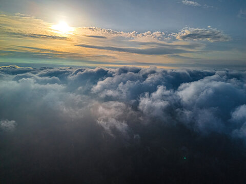 Aerial view of dense cloud formations illuminated by the warm golden light of the setting sun above the landscape of Vidzeme, Latvia.