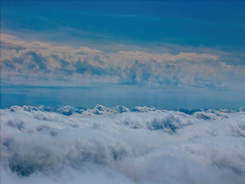 Aerial view of a dense layer of white clouds stretching towards the horizon under a bright blue sky in Vidzeme, Latvia.