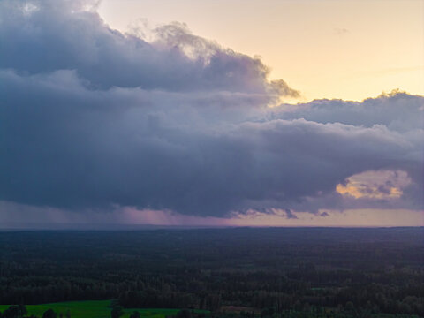 Aerial view of dramatic storm clouds gathering over the vast forests and green fields of the region, Vidzeme, Latvia.