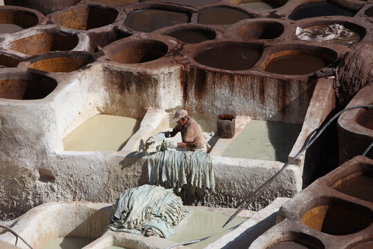 View of a worker processing leather hides in the stone vats of a traditional tannery in Morocco.