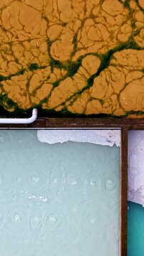 Aerial view of industrial water treatment basins with textured sludge and aeration patterns in Bauska, Bauska Municipality, Latvia.