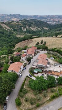 Scenic aerial drone view of green rolling hills and countryside houses nestled among olive trees in province of Teramo Abruzzo region landscape Italy.
