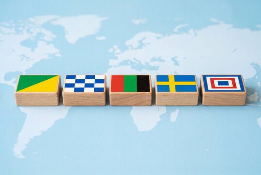 Five wooden blocks with colorful geometric patterns lined up on a light blue world map background