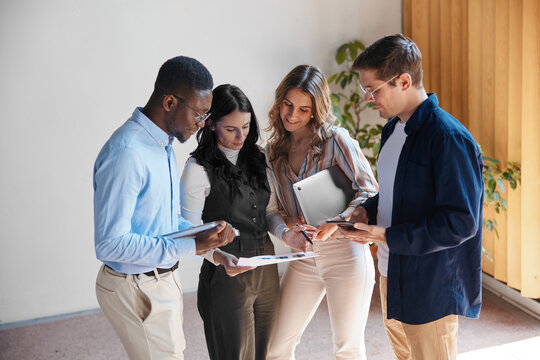 Diverse business team collaborating and brainstorming strategy in a modern office, analyzing data and discussing new project ideas, fostering innovation and teamwork