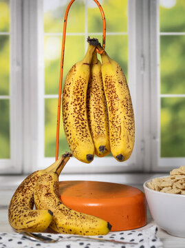 Vertical photo of very ripe bananas and bowl of cereal by kitchen window. 