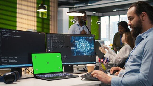 Office administrator uses an isolated laptop with a chroma key screen to automate repetitive tasks with AI scripts and speed up feature implementation.