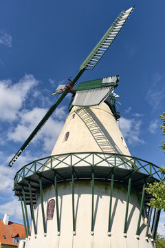 Sonderborg, Denmark - 07 July 2026: View of Slotsmollen, a historic windmill with green wooden sails and a white stone base under a clear blue sky.