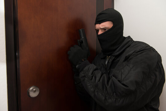Burglar Standing Behind The Door With A Gun