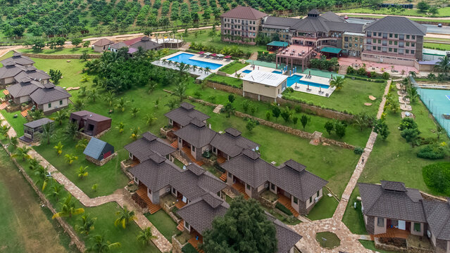 Akosombo, Eastern Region, Ghana - 11 September 2022: Aerial view of The Peninsula Resort featuring multiple guest villas, swimming pools, and landscaped grounds in a lush tropical setting.