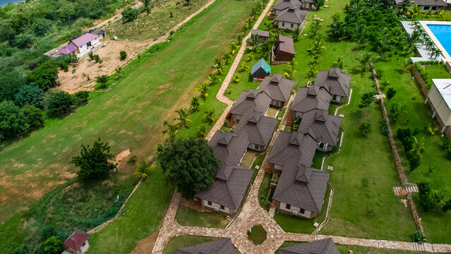 Akosombo, Ghana - 11 September 2022: Aerial view of The Peninsula Resort featuring a cluster of villas with dark roofs, stone pathways, and lush green lawns.