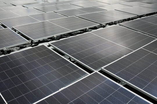 Aerial view of floating solar panels arranged in a grid pattern on the water surface in Berau Regency, East Kalimantan, Indonesia.