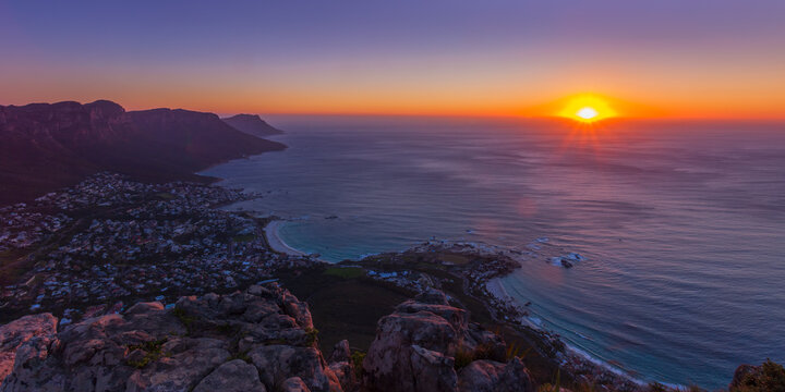 View of the coastline and mountains at sunset with the sun setting over the Atlantic Ocean in South Africa.