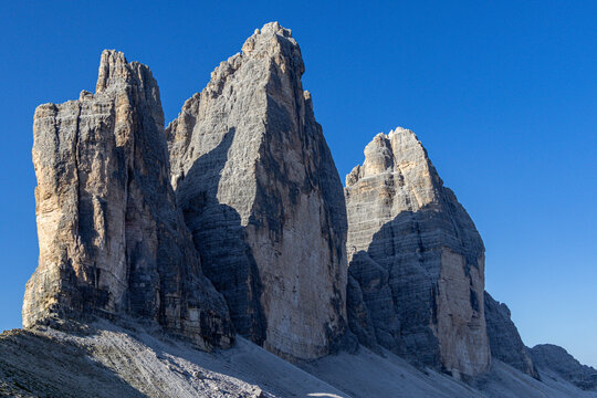 View of Tre Cime di Lavaredo with its iconic jagged limestone peaks rising against a clear blue sky in Auronzo di Cadore, Veneto, Italy.