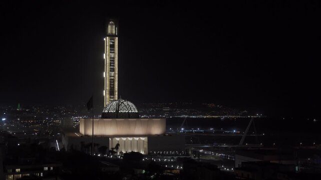 Aerial view of the illuminated Great Mosque of Algiers with its towering minaret and dome glowing against the dark night sky, Algeria.