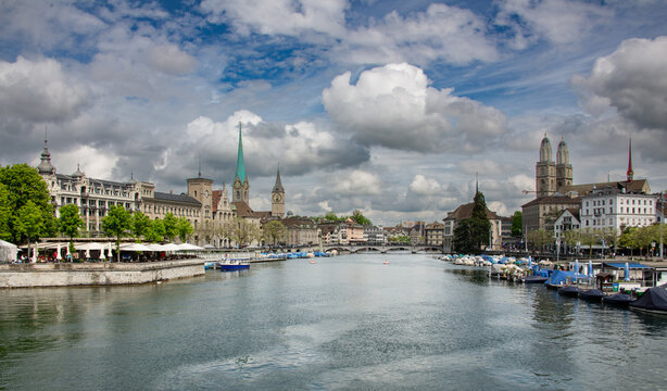 View of the Limmat river in Zurich with historic buildings, church spires, and boats moored along the banks in Zurich, Zurich, Switzerland.
