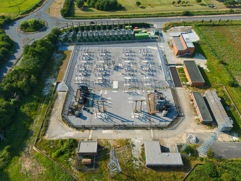 Aerial view of an electrical substation and containerized industrial generator compressor units surrounded by green fields and infrastructure in Immingham, England, United Kingdom.
