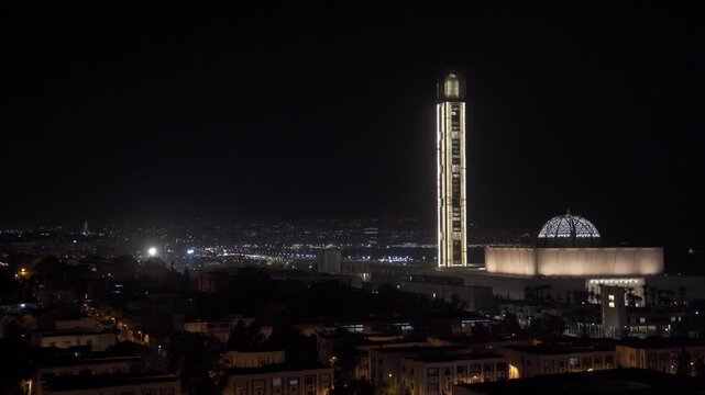 Aerial view of the illuminated Great Mosque of Algiers with its tall minaret and dome glowing against the dark night sky, Algeria.