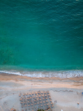 Aerial view of a pristine beach with turquoise water, white sand, and rows of beach umbrellas in Albania.
