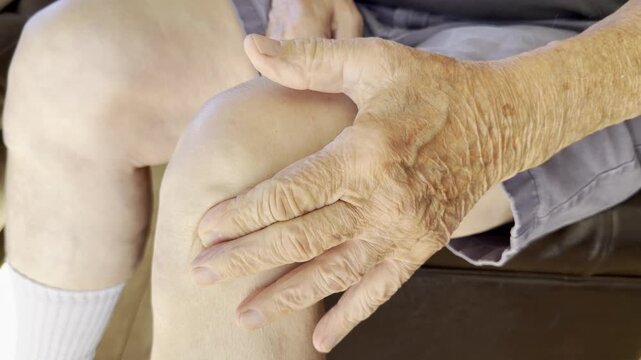Older man carefully massages a sore knee	