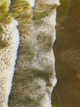 Aerial view of rhythmic ocean waves with white foam crashing against the shore at Ayampe, Manabi, Ecuador.