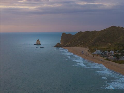 Aerial view of the coastline at Ayampe beach with rocky cliffs, crashing waves, and the small town nestled against the hills in Ayampe, Manabi, Ecuador.