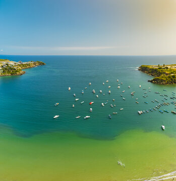 Aerial view of Ayangue Bay filled with numerous small fishing boats floating in turquoise waters surrounded by coastal cliffs in Ayangue, Santa Elena, Ecuador.