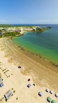 Aerial view of the turquoise waters and sandy beach of Ayangue with colorful umbrellas scattered along the shore in Ayangue, Santa Elena, Ecuador.
