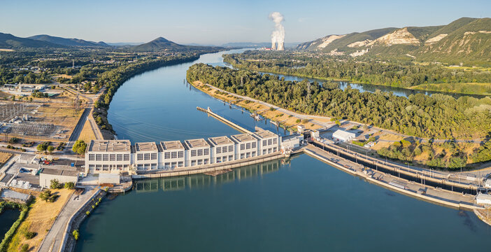 Aerial view of the Rhone River featuring the hydroelectric dam and the Cruas Nuclear Power Plant, surrounded by lush vegetation in Saulce-sur-Rhone, Auvergne-Rhone-Alpes, France.