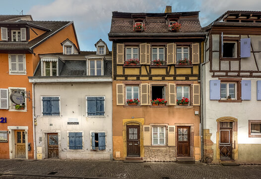 View of colorful half-timbered houses with flower boxes and wooden shutters in the historic town center of Colmar, Grand Est, France.