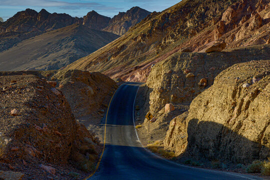 View of a winding road through the rugged, rocky desert landscape of Death Valley National Park's backcountry in Death Valley, California, United States.