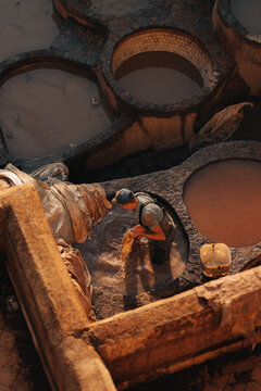 Fes, Morocco - 11 November 2025: View of a worker cleaning leather in a stone vat at the historic Chouara Tannery, surrounded by traditional dye pits.