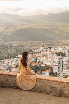 Chefchaouen, Tangier-Tetouan-Al Ho, Morocco - 14 November 2025: View of a woman sitting on a stone wall overlooking the blue-washed buildings of Chefchaouen in the Rif mountains.