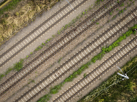 Aerial view of parallel railway tracks at a train repair station with gravel ballast and green vegetation in Krakow, Lesser Poland Voivode, Poland.