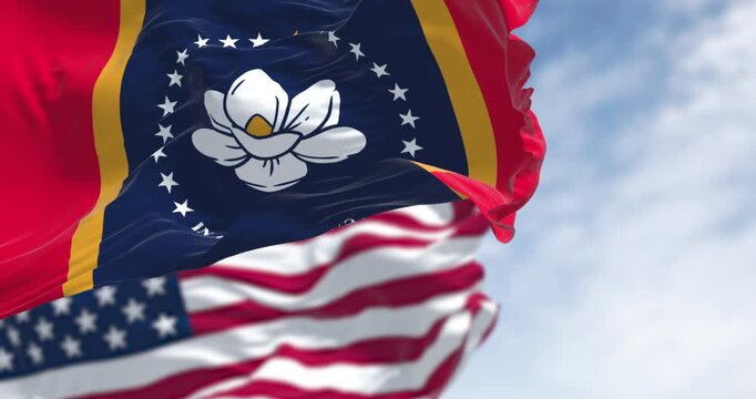 Mississippi state flags waving with the American flag on a clear day