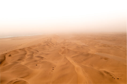 Namibia Desert, Namibia - 10 September 2023: View of the vast sand dunes of the Namib Desert meeting the Atlantic Ocean under a hazy sky.