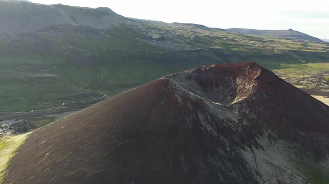 Aerial view of Ytri-Raudarmelskula volcanic crater with its distinct reddish slopes and surrounding green landscape in Raudhamelur, Eyja- og Miklaholtshr, Iceland.