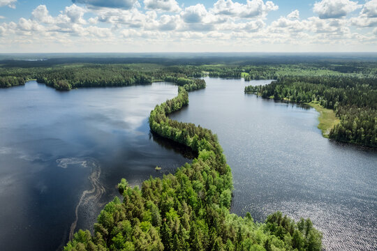 Aerial view of the narrow, forested ridge of Liesjarvi National Park separating the dark blue waters of the lake under a bright sky in Tammela, Finland.