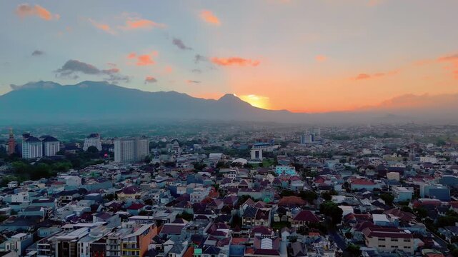 Aerial view of Malang city at sunset with Gunung Butak, Gunung Kawi, and Gunung Panderman as one called Barisan Putri Tidur in the background, Malang, East Java, Indonesia.