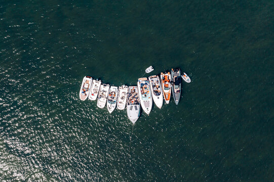 Poole, England, United Kingdom - 10 July 2021: Aerial view of a group of motorboats moored together in the calm dark water of the harbour.
