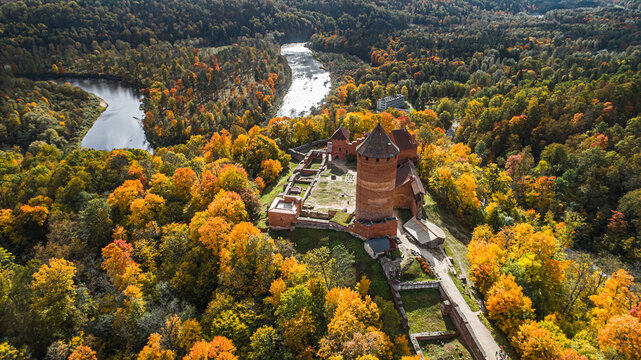Aerial view of Turaida Castle surrounded by vibrant autumn forests and the winding Gauja River in Sigulda, Sigulda Municipality, Latvia.