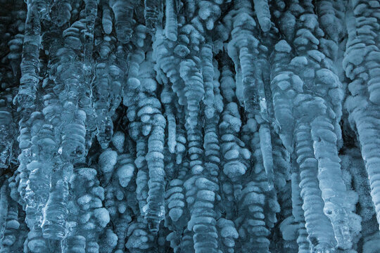 View of Lake Baikal icicles forming intricate frozen patterns on a rocky cave wall in Khuzhir, Irkutsk Oblast, Russia.