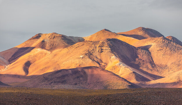 View of the arid, sunlit mountains of the El Tatio region with rocky slopes and dramatic shadows in Antofagasta, Antofagasta, Chile.