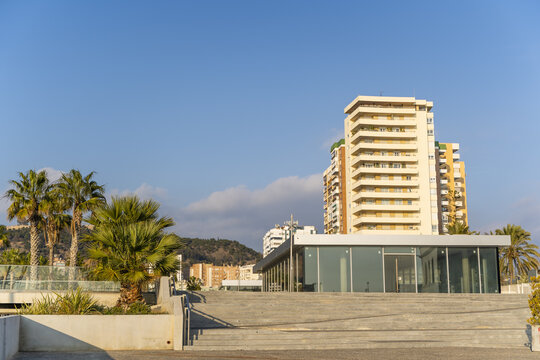 Malaga, Spain - 10 January 2020: View of the Palmeral de Las Sorpresas promenade and modern architecture at the port of Malaga under a clear blue sky.