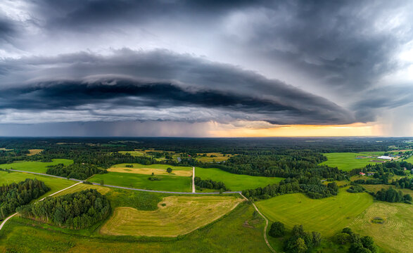 Aerial view of a dramatic supercell storm cloud formation over the lush green fields and forests of the Latvian countryside, Latvia.
