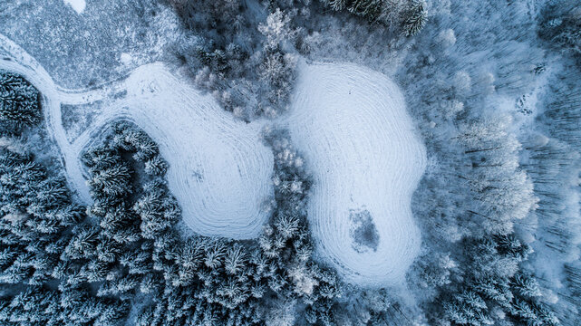 Aerial view of snow-covered forest and fields in winter in Latvia.